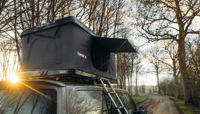 TentBox Classic roof tent parked on roadside camping spot, with trees in the background